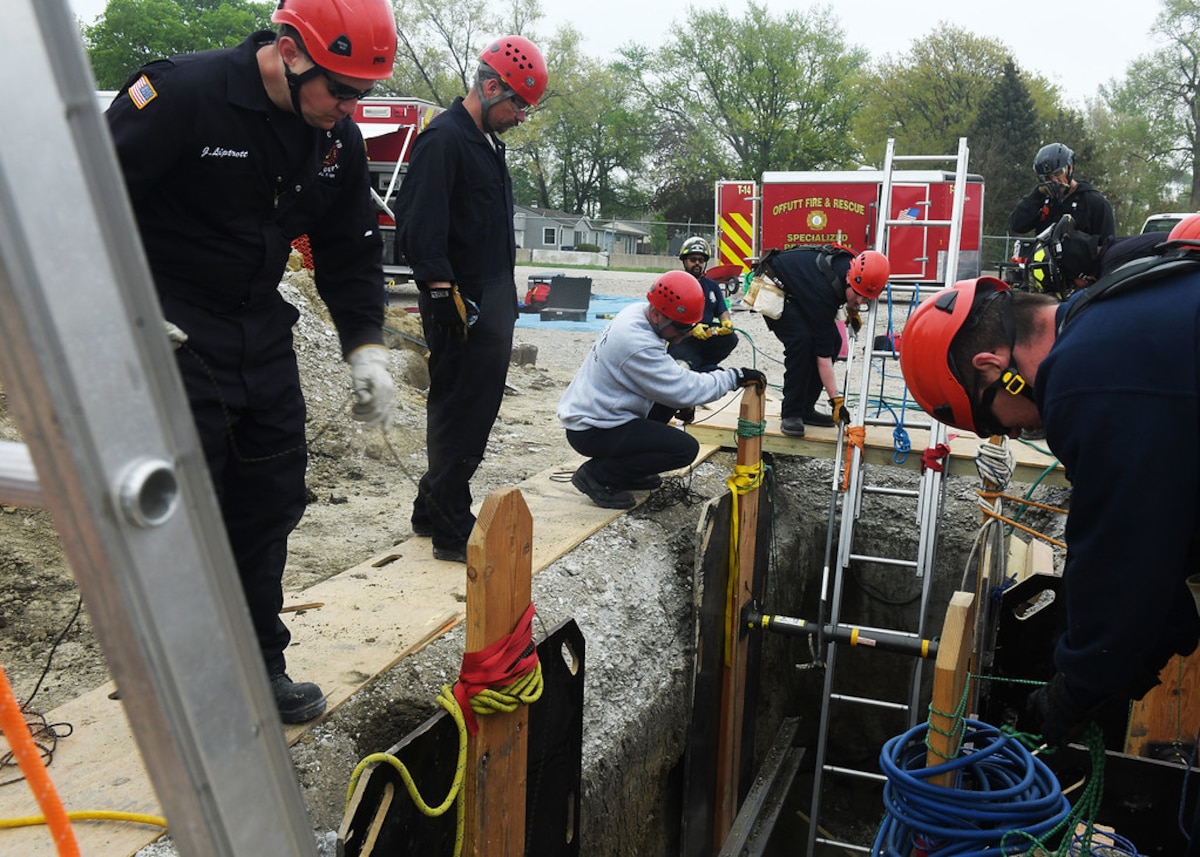 Firefighters work around the top of a trench