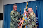 two military officers pass a flag