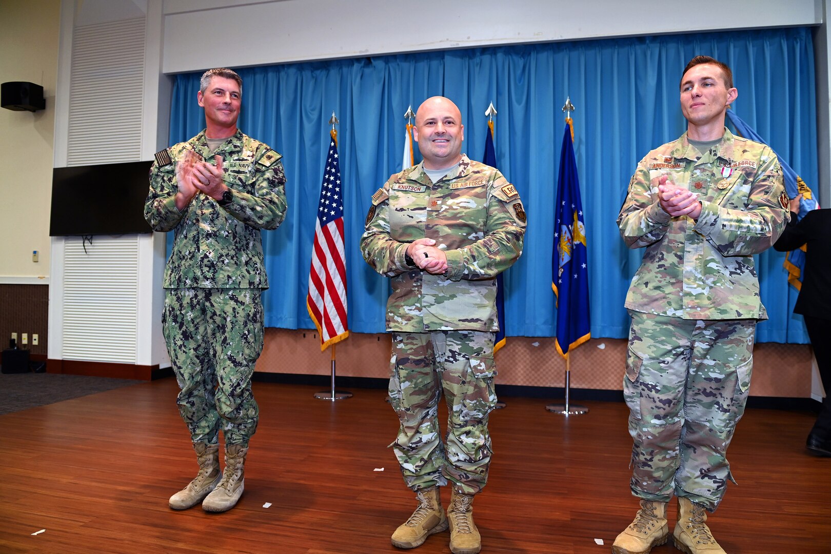 three military officers stand together in uniform