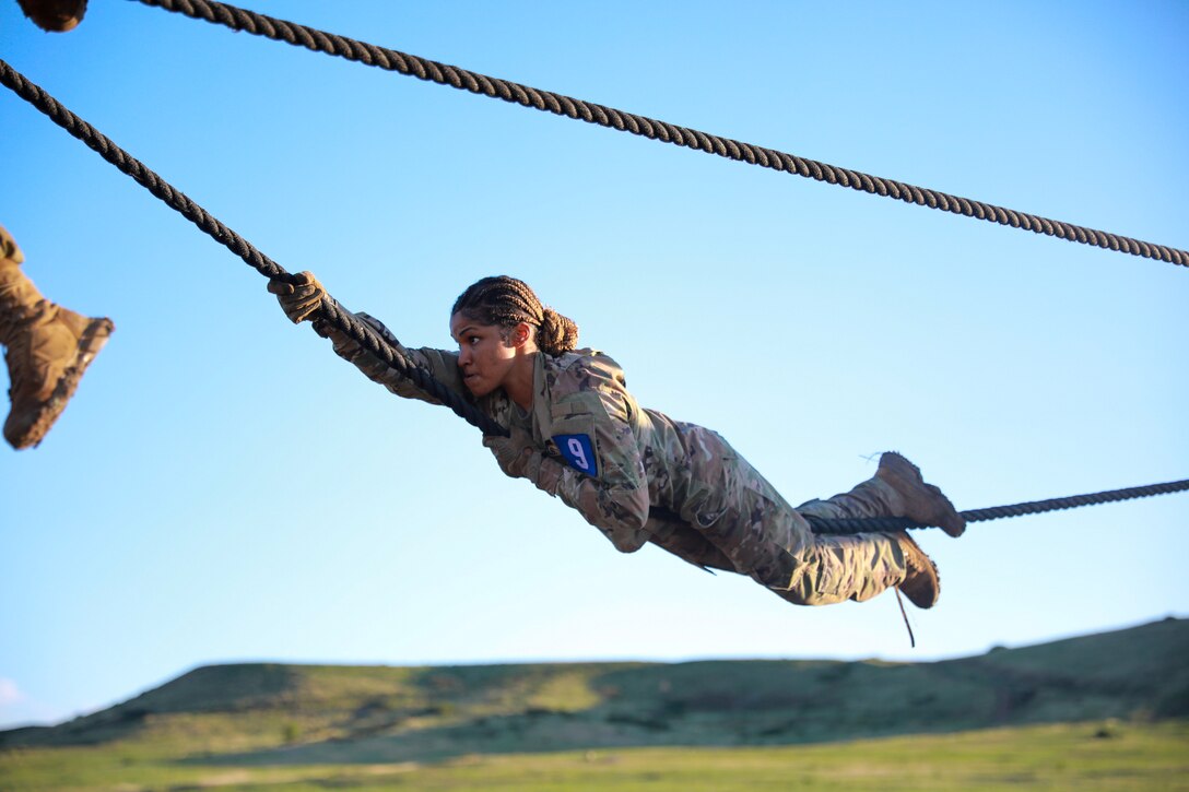 A soldier pulls herself on ropes during a competition.