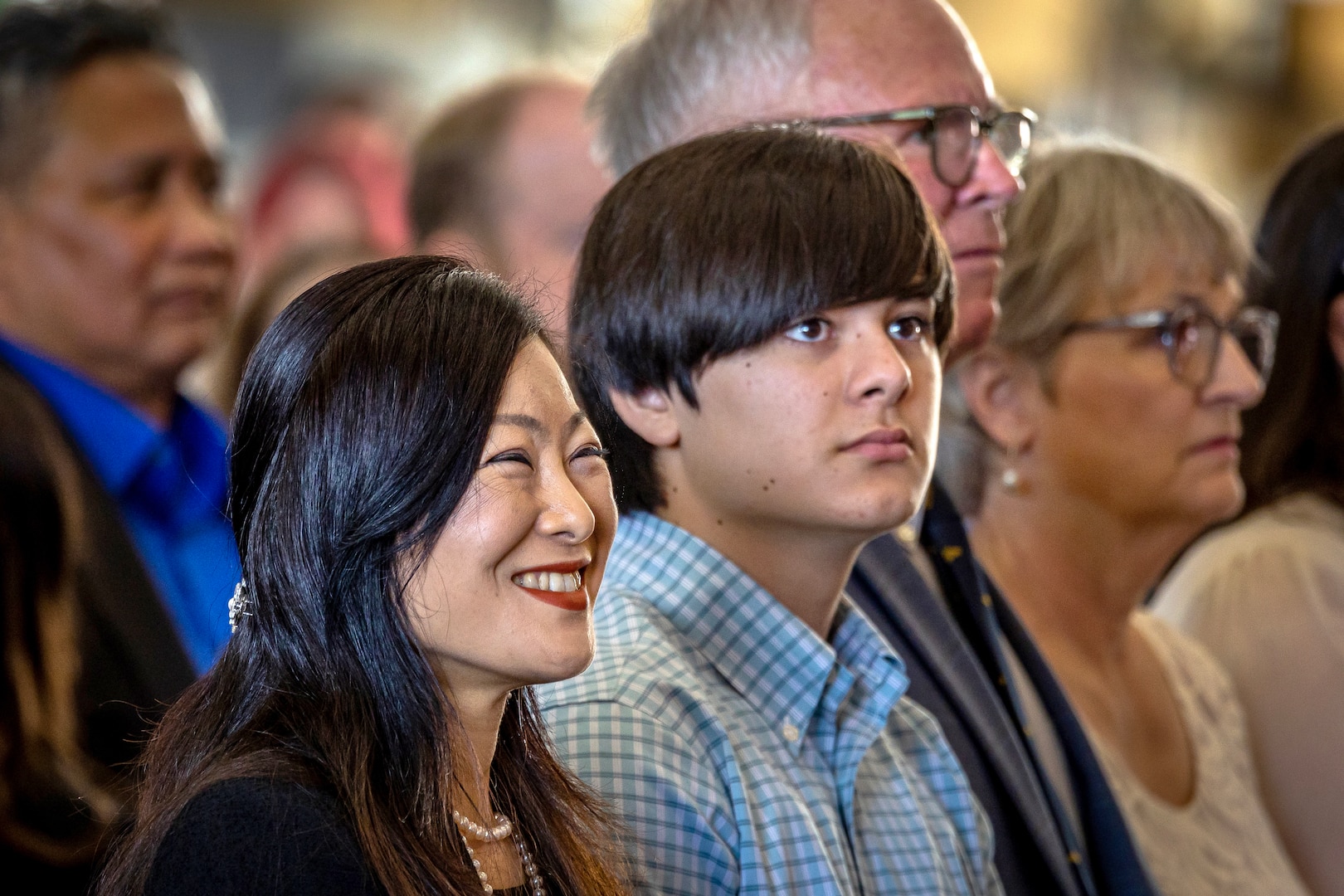 Capt. JD Crinklaw's wife, Junko, left, and son, Kai, listen to remarks by outgoing commander Capt. Jim Mosman May 25, 2023, during a Change of Command Ceremony at Puget Sound Naval Shipyard & Intermediate Maintenance Facility in Bremerton, Washington. (U.S. Navy photo by Scott Hansen)