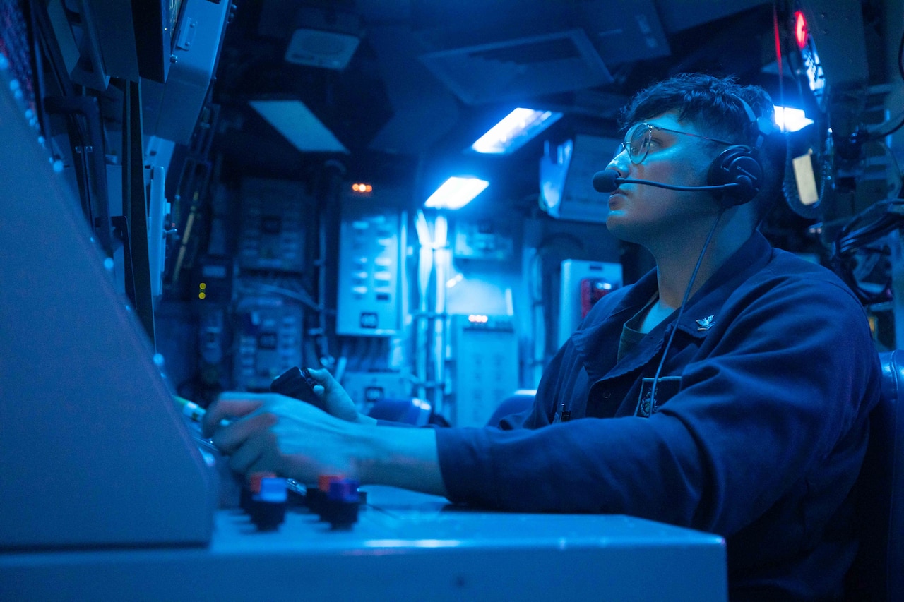 A sailor operates electronic gear.