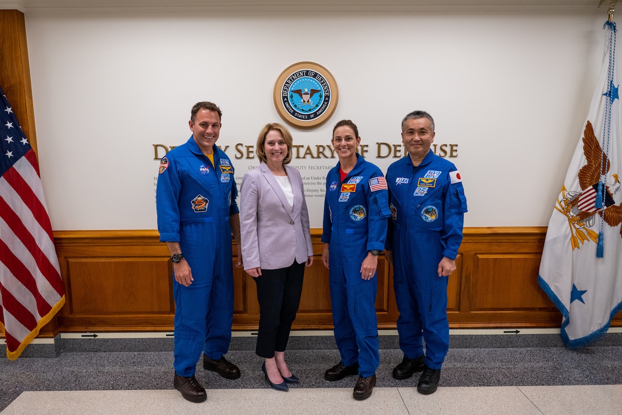 A woman in a suit poses with men and women wearing flight suits.