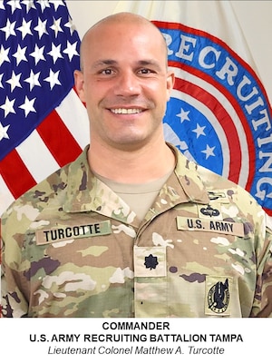 man wearing u.s. army uniform standing in front of flags.