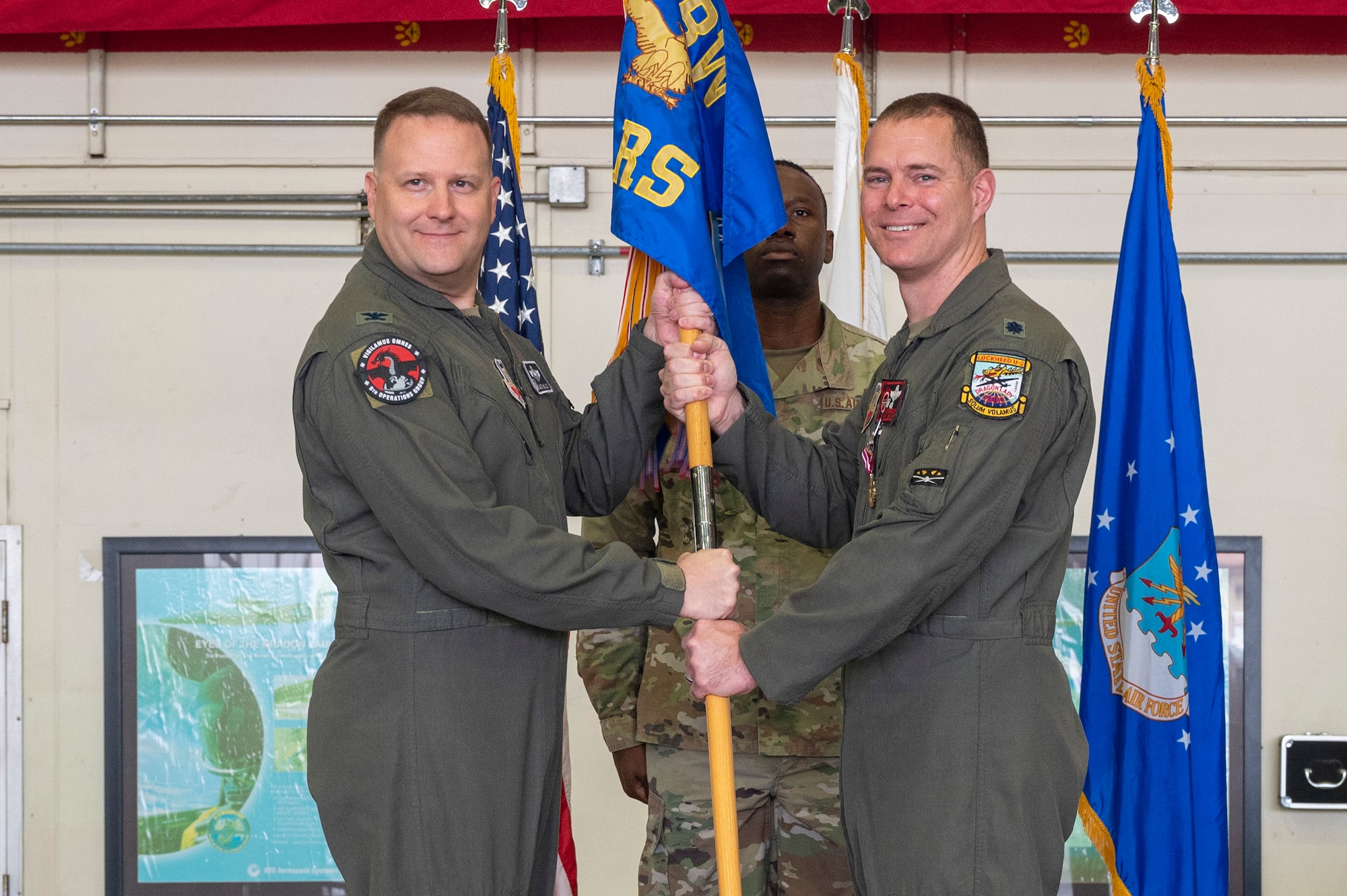U.S. Air Force Lt. Col. Michael Opresko, 5th Reconnaissance Squadron commander, passes the guidon to Col. Jason Bialon, left, 9th Operations Group commander, at Osan Air Base, Republic of Korea, June 2, 2023. In a change of command ceremony, the guidon symbolizes the transfer of command and the authority and responsibility associated with it. (U.S. Air Force photo by Airman 1st Class Aaron Edwards)