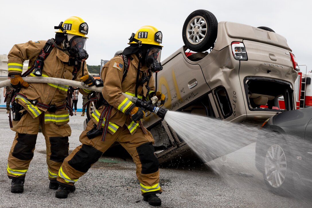 Firefighters with Marine Corps Installations Pacific Fire and Emergency Services use a hose to extinguish a simulated fire in a multi-vehicle accident crisis response drill during Exercise Constant Vigilance 2022 on Camp Foster, Okinawa, Japan, Oct. 19, 2022. The annual drill was held to convey the readiness and capabilities of various installations and first responders in the event of an emergency. CV22 is a Force Protection Condition and crisis response evaluation to validate regional installations, camps, and tenant antiterrorism plans and policies. (U.S. Marine Corps photo by Lance Cpl. Thomas Sheng)