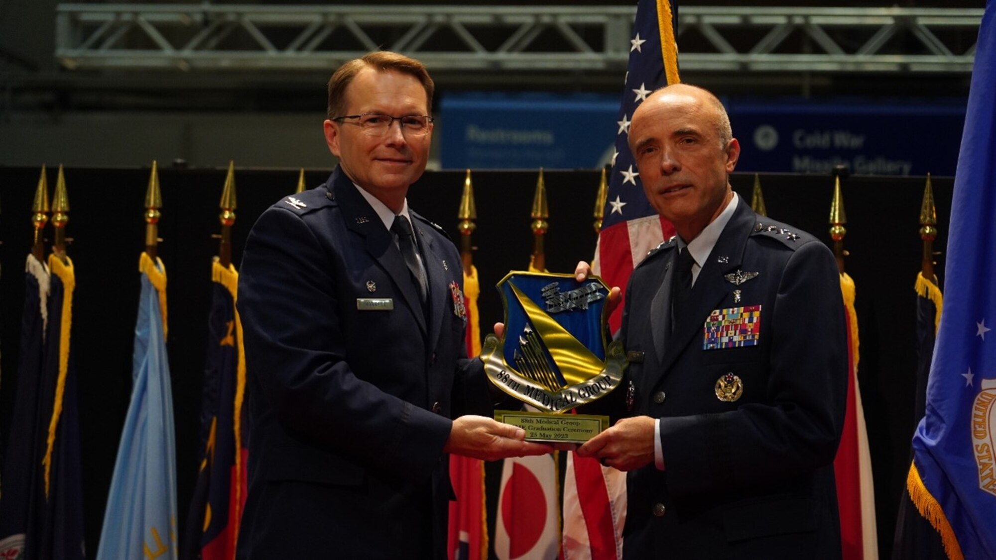 88th Medical Group commander, awards a plaque of appreciation to Lt. Gen. Robert Miller, Air Force Surgeon General  at the Wright-Patterson Medical Center’s residency graduation