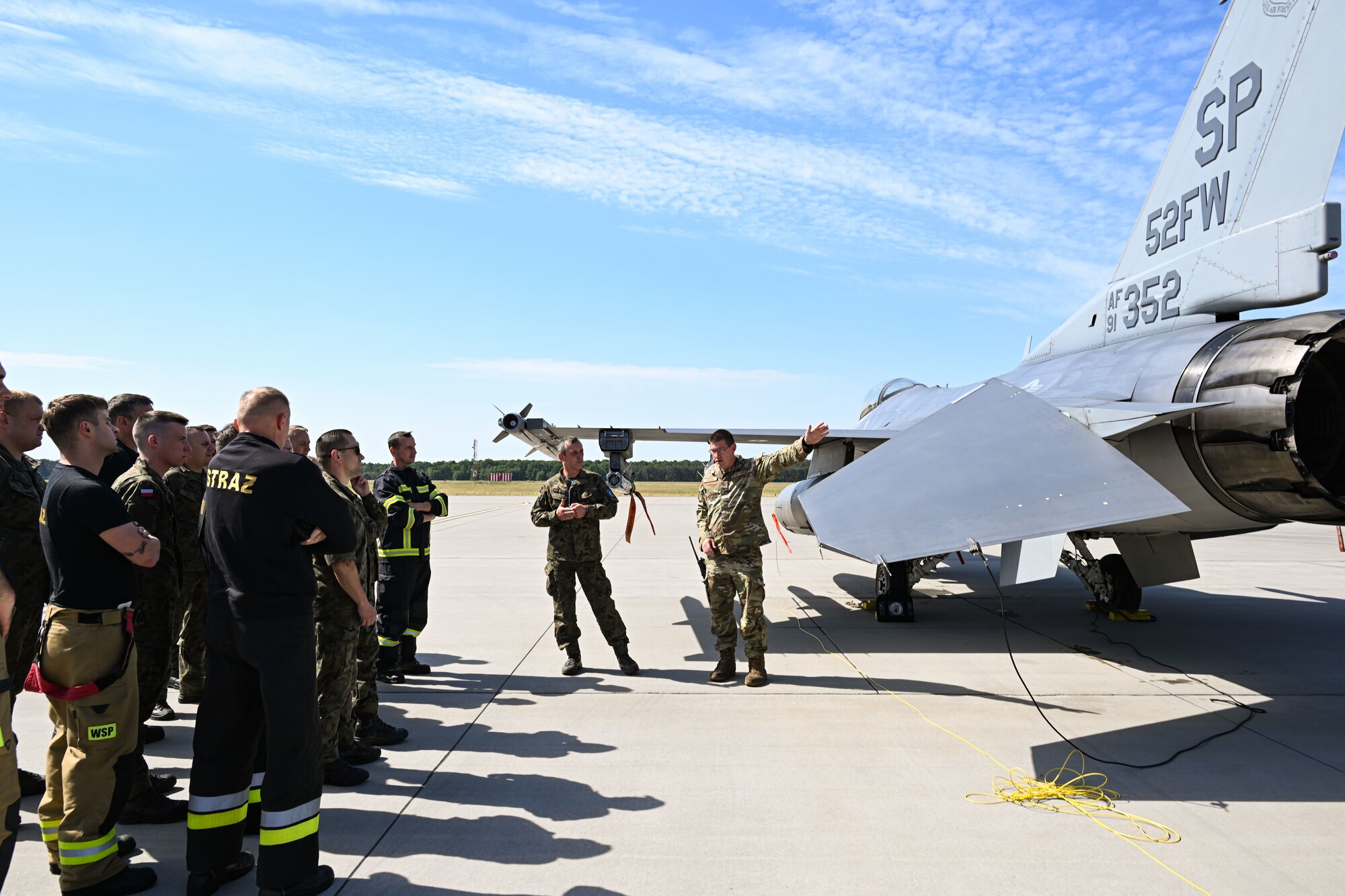 U.S. Air Force Tech. Sgt. Joshua Gorman, 480th Fighter Generation Squadron Crash Damaged Disabled Aircraft Recovery (CDDAR) team chief, left, shows Polish fire department members with the 33rd Airlift Base aircraft safing pins on a U.S. F-16 Fighting Falcon at Powidz Air Base, Poland