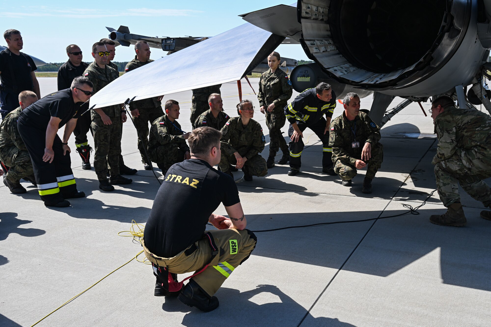 U.S. Air Force Tech. Sgt. Joshua Gorman, 480th Fighter Generation Squadron Crash Damaged Disabled Aircraft Recovery (CDDAR) team chief, briefs Polish fire department members with the 33rd Airlift Base about various aircraft emergency procedures at Powidz Air Base, Poland