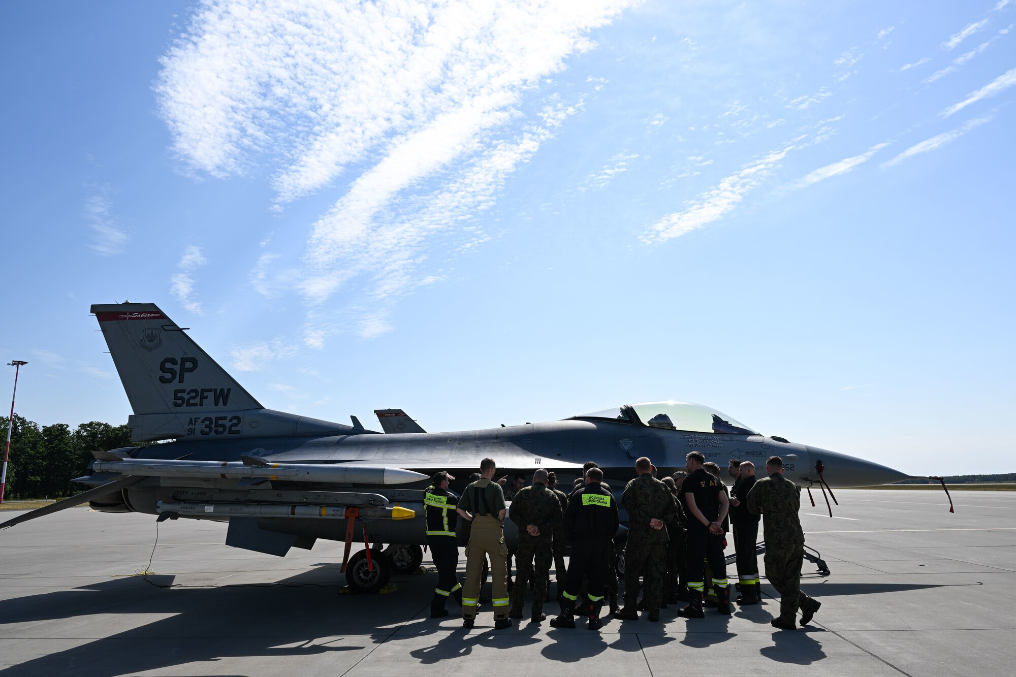 Polish fire department members with the 33rd Airlift Wing gather for a brief on U.S. F-16 Fighting Falcon emergency procedures at Powidz Air Base, Poland
