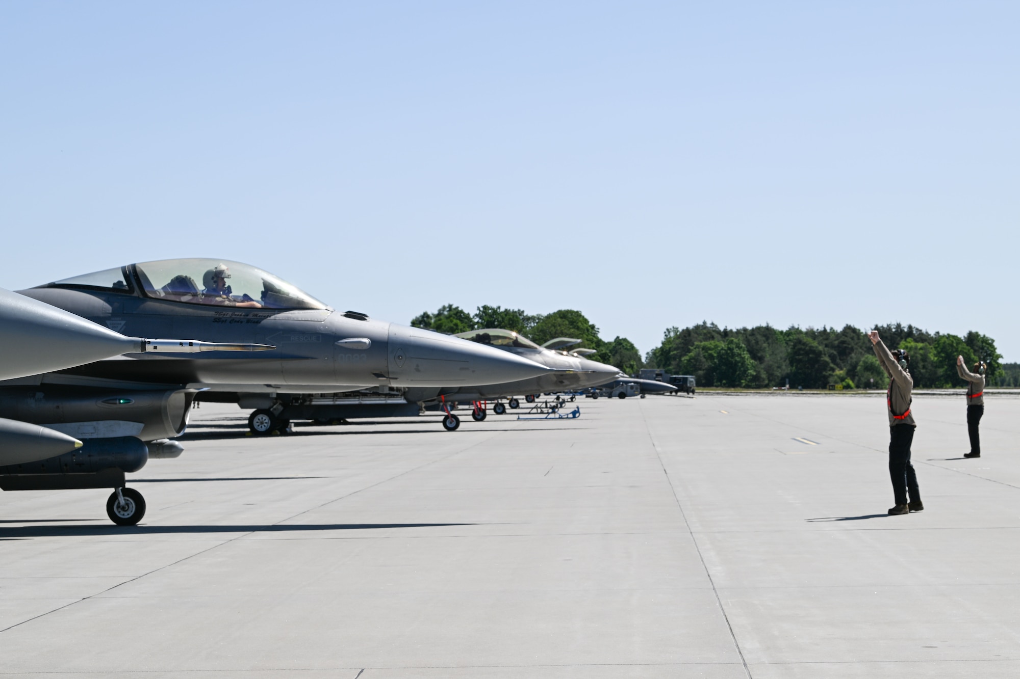 U.S. Airman 1st Class Nestor Mendoza, 480th Fighter Generation Squadron crew chief, left, and Airman 1st Class Jahvan Thom, 480th FGS crew chief, direct F-16 Fighting Falcons with the 480th Fighter Squadron upon arrival to Powidz Air Base, Poland