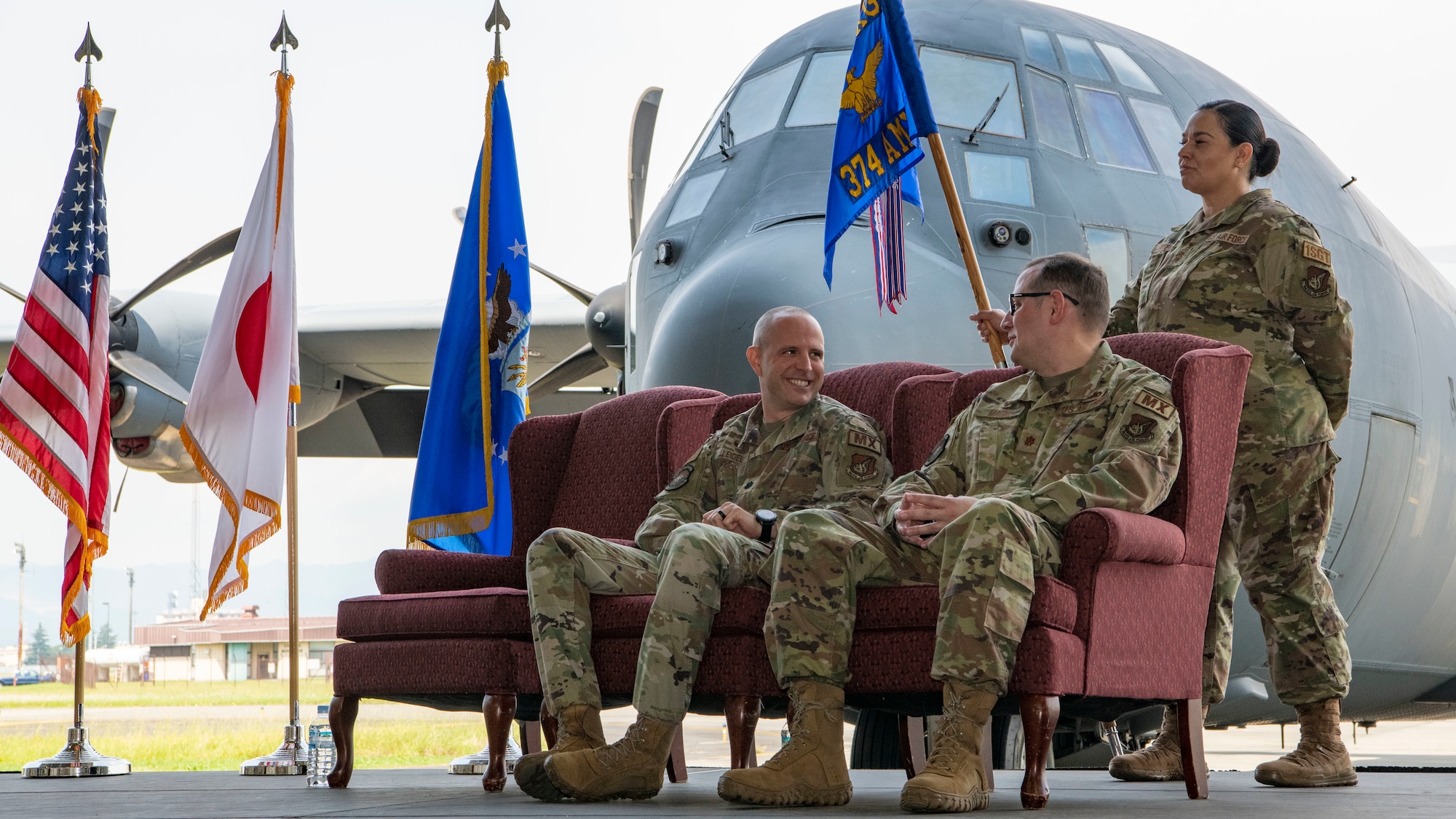 Two military men sit in chairs and look at one another