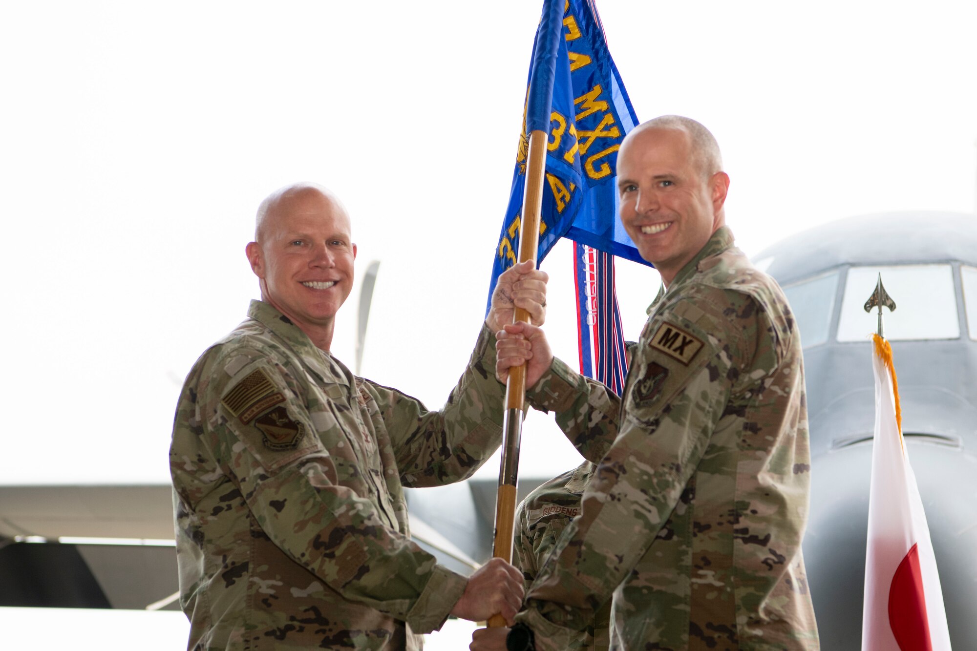 Military man receives a squadron flag on a pole from another military man