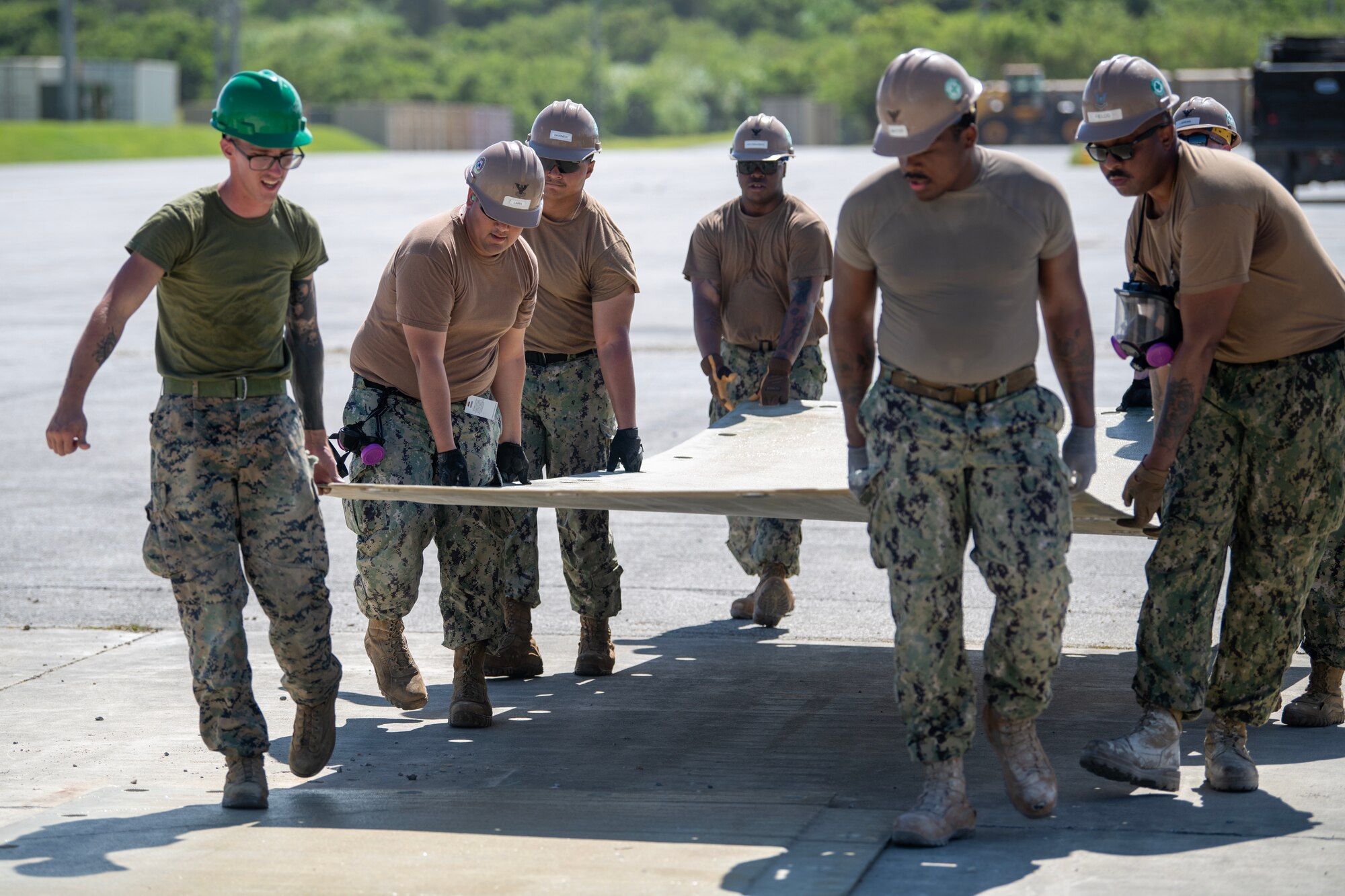 U.S. Navy sailors and Marines carrying concrete curing mats