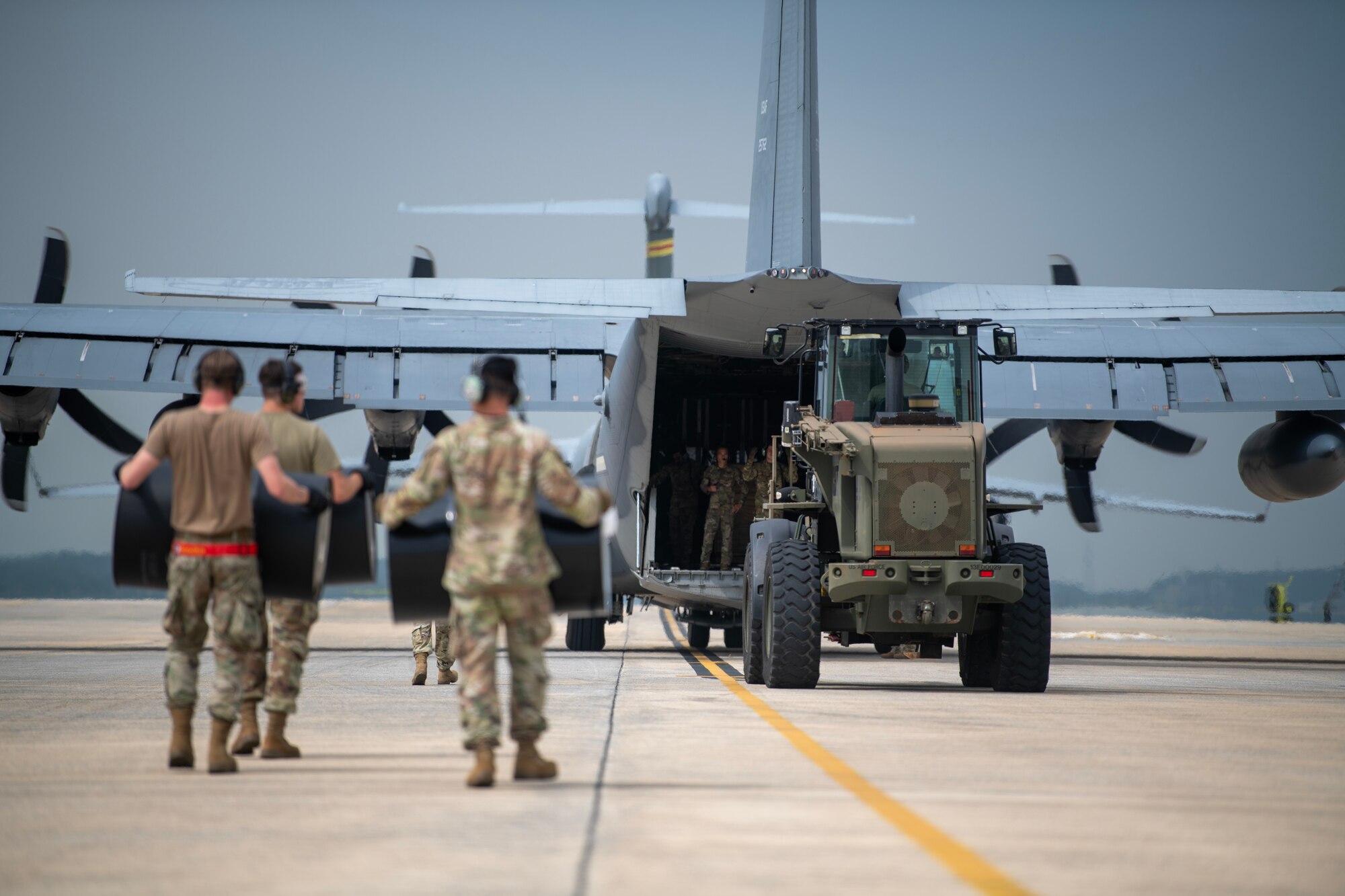 Airmen carrying barrels towards a C-130 for an offloading method B training