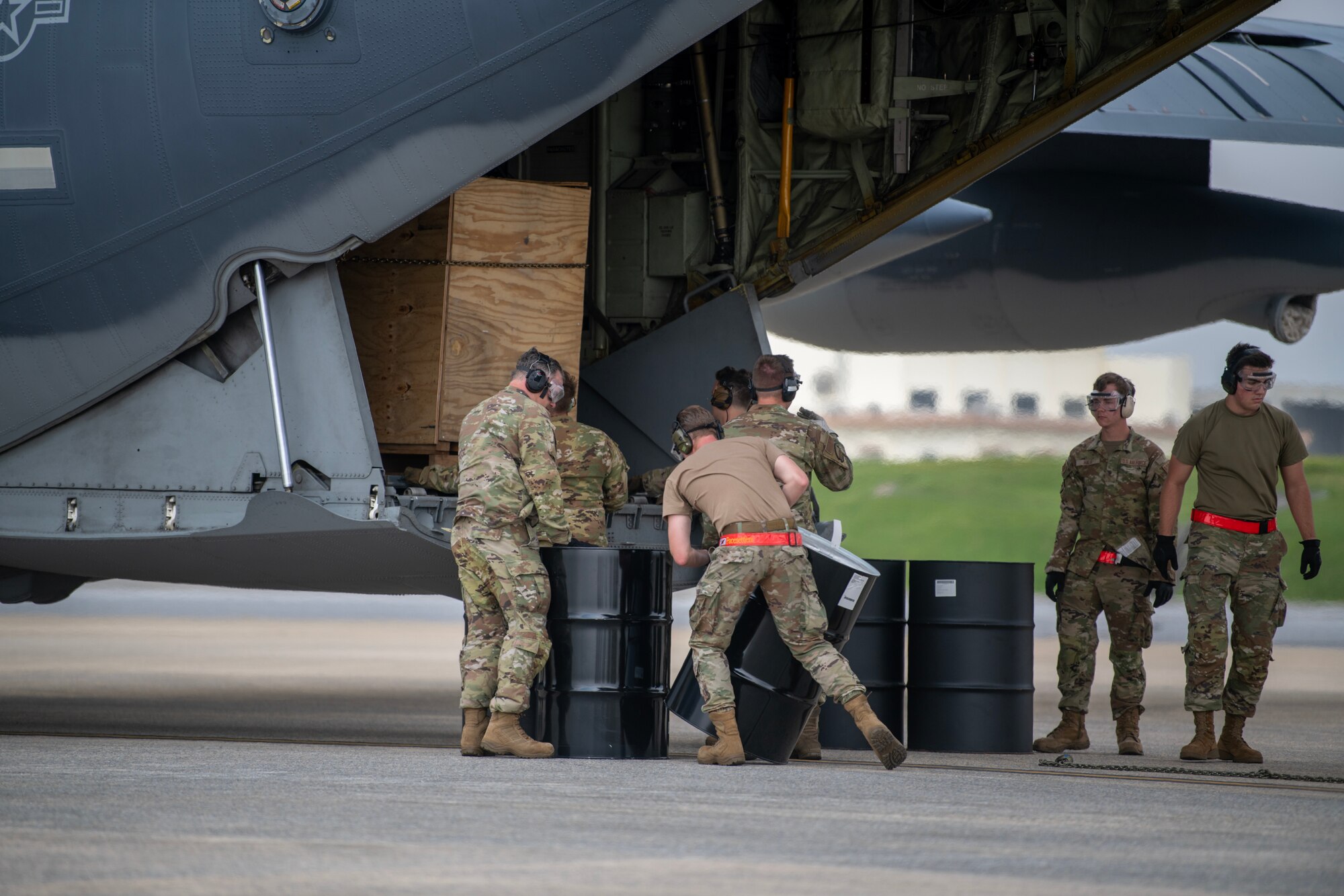 Airmen positioning barrels to distribute the weight of an unloading payload