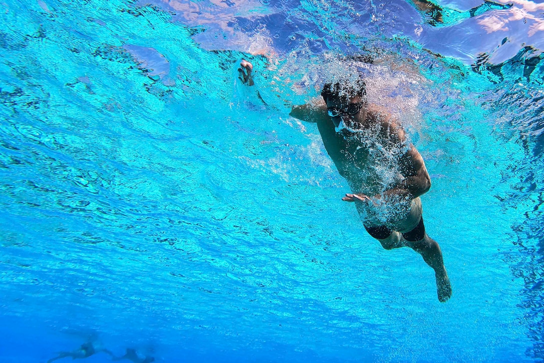 A Marine swims in a pool.