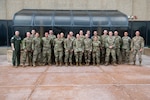 Military members in uniform pose for a group photo
