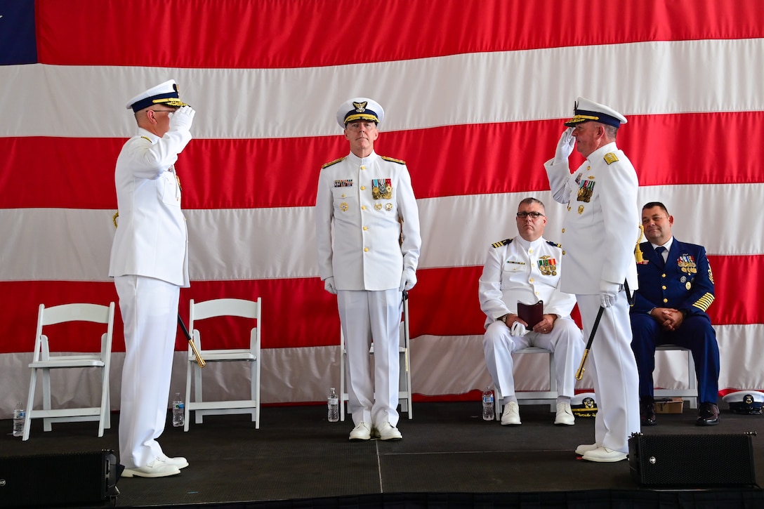 Vice Adm. Kevin Lunday, Coast Guard Atlantic Area Commander, oversees Rear Adm. Brendan McPherson, the former Seventh District Commander, and Rear Adm. Douglas Schofield, the Seventh District Commander, render a salute during a change of command ceremony at Air Station Miami in Opa-locka, Florida, June 9, 2023. During the ceremony Schofield relieved McPherson as the Seventh District Commander and Director of Department of Homeland Security Joint Task Force - Southeast. (U.S. Coast Guard photo by Petty Officer 3rd Class Eric Rodriguez)