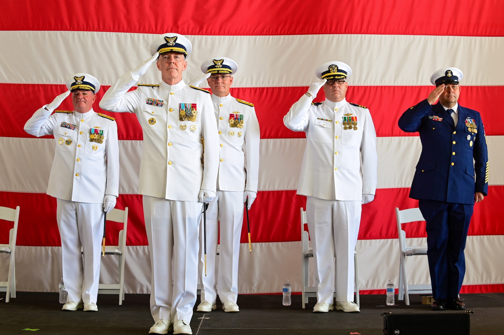 Vice Adm. Kevin Lunday, Coast Guard Atlantic Area Commander, oversees Rear Adm. Brendan McPherson, the former Seventh District Commander, and Rear Adm. Douglas Schofield, the Seventh District Commander, render a salute during a change of command ceremony at Air Station Miami in Opa-locka, Florida, June 9, 2023. During the ceremony Schofield relieved McPherson as the Seventh District Commander and Director of Department of Homeland Security Joint Task Force - Southeast. (U.S. Coast Guard photo by Petty Officer 3rd Class Eric Rodriguez)