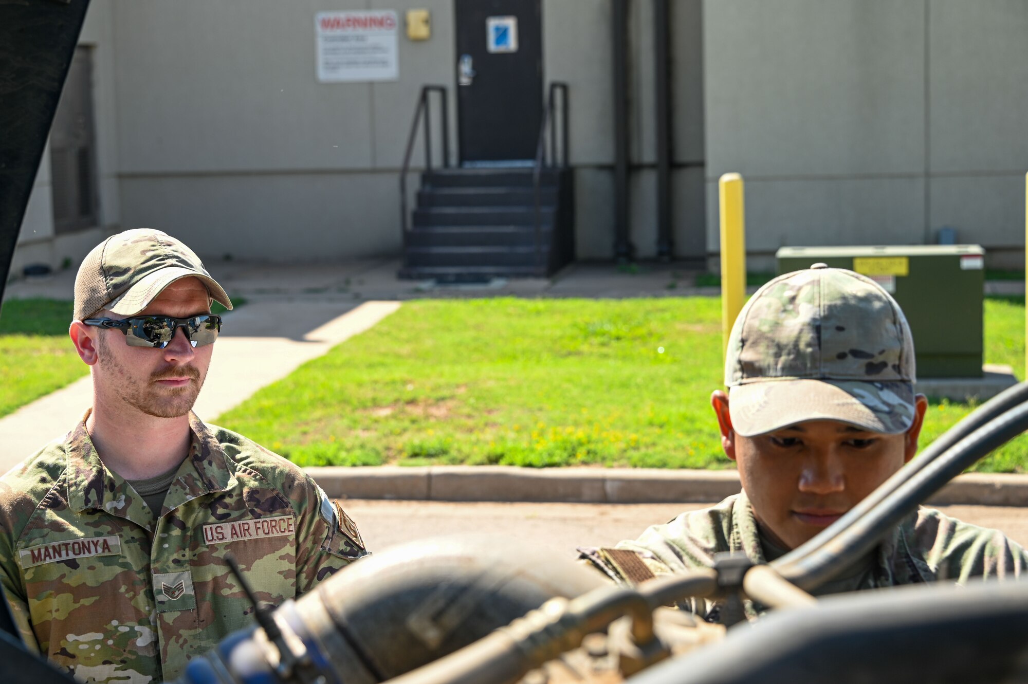 U.S. Air Force Staff Sgt. Benjamin Mantonya, 97th Logistics Readiness Squadron (LRS) training, validation, and operations examiner, watches as Airman 1st Class Rolfo Dogillo, 97th LRS ground transportation operator, checks over a vehicle at Altus Air Force Base, Oklahoma, May 30, 2023. Mantonya certifies other ground transportation Airmen in multiple areas of expertise. (U.S. Air Force photo by Senior Airman Kayla Christenson)