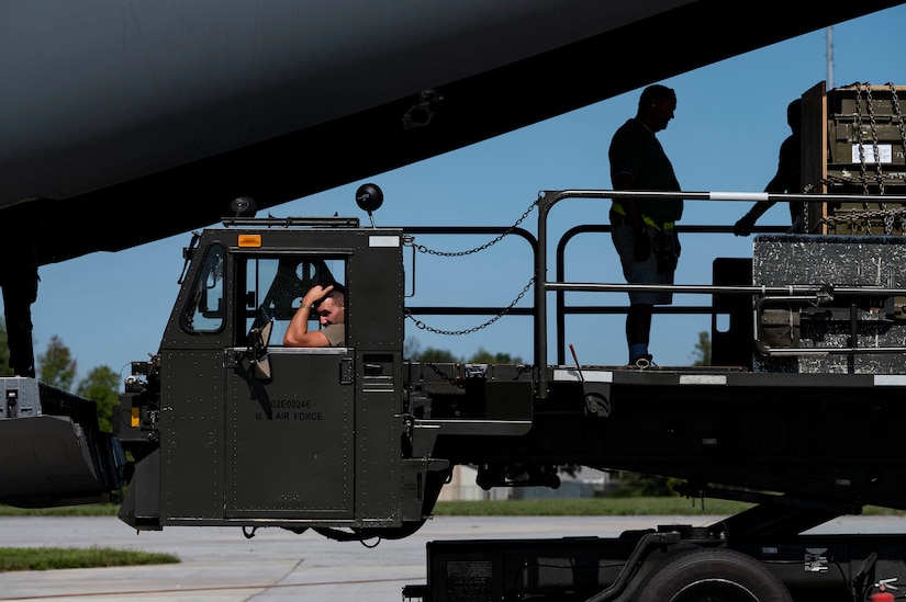 A cargo-loading vehicle sits by the ramp of a cargo plane.