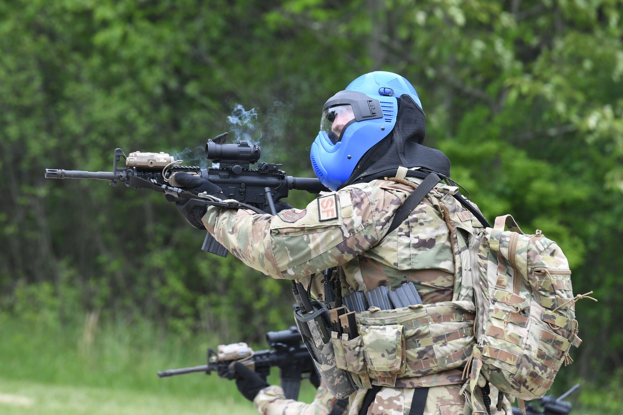 An Air Force Reserve Command Security Forces member fires dye-marker rounds from his M4 carbine at opposing force members during an area security operations exercise at the Integrated Defense Leadership Course at Camp James A. Garfield Joint Military Training Center, Ohio, May 19, 2023.