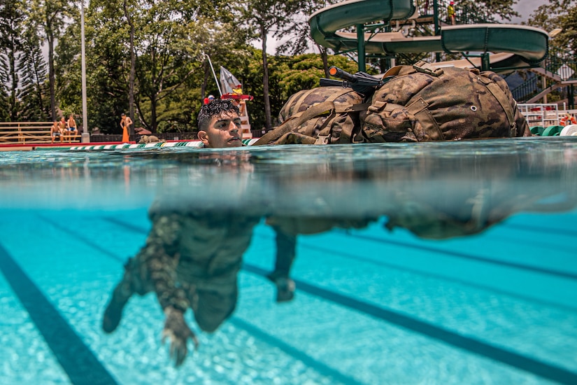 U.S. Army Soldiers swims with his rucksack during a combat water survival training course for the USARPAC Best Squad Competition 2023, at the Richardson Pool on Schofield Barracks, Hawaii, June 7, 2023.