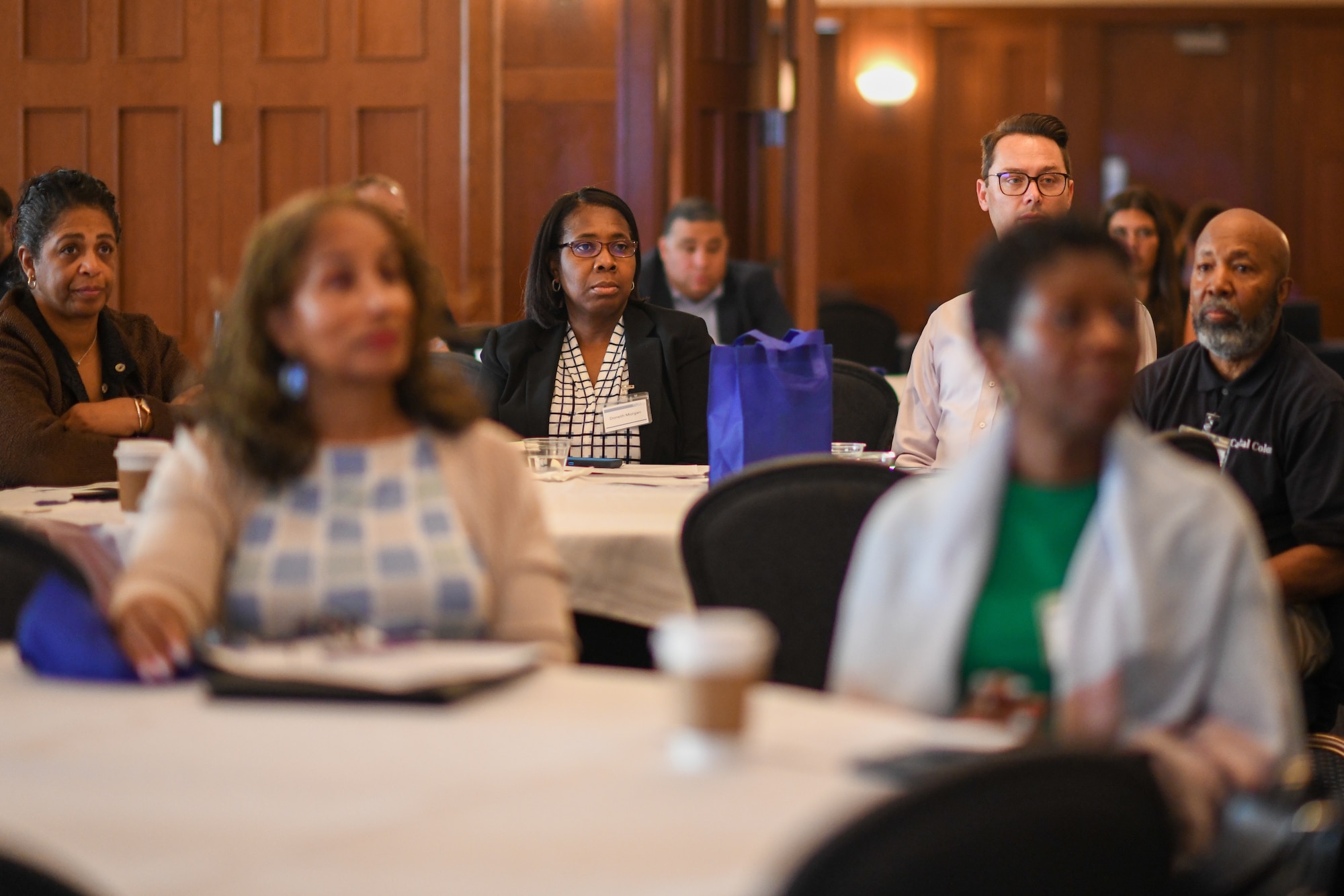 People sitting a tables listening to a briefing.