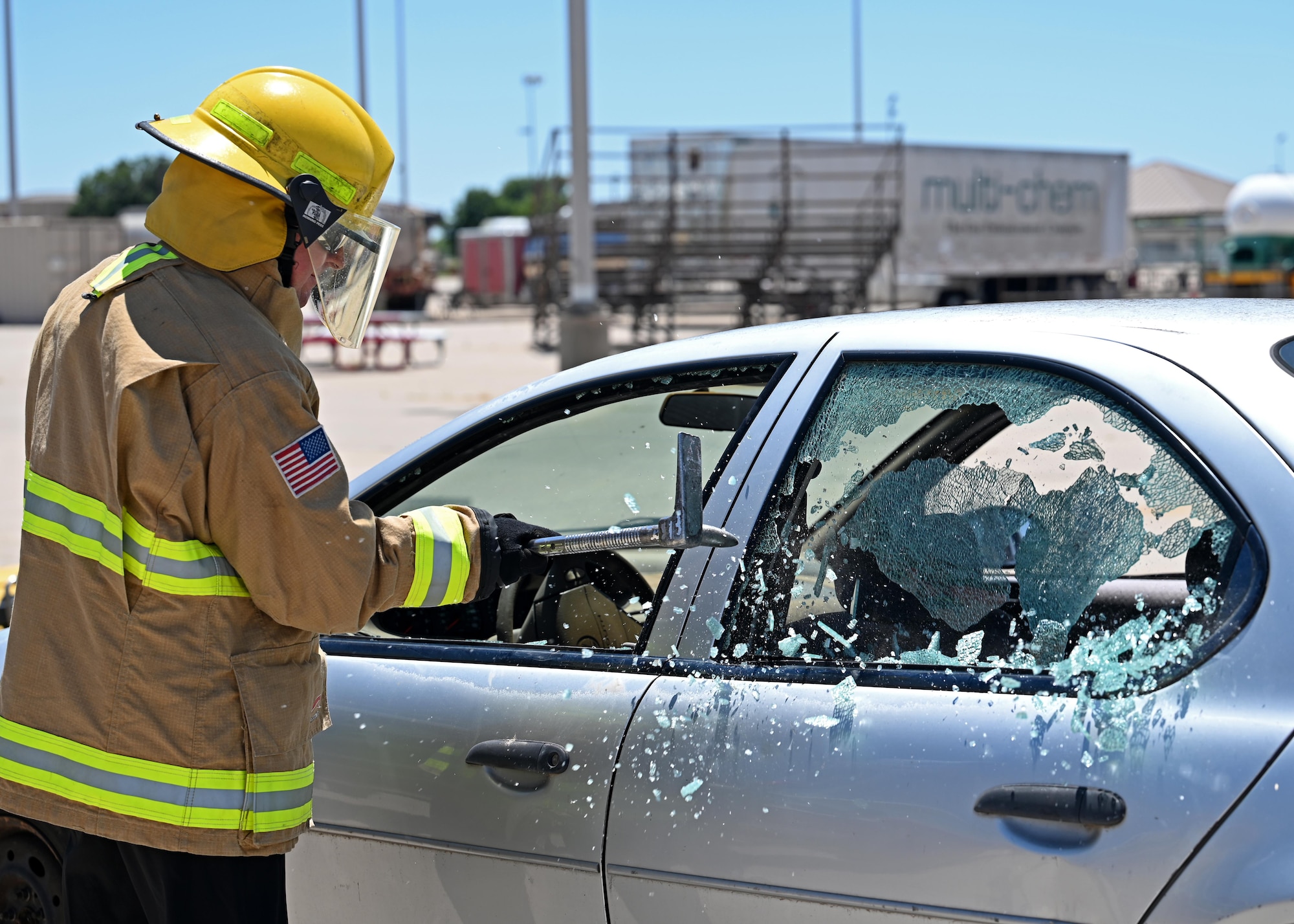 A 17th Training Wing honorary commander, Scott Creesy, breaks a car window at Goodfellow Air Force Base, Texas, June 8, 2023. Breaking the car window allowed firefighters to use hydraulic rescue tools to detach the door so they can provide care to a car accident victim. (U.S. Air Force photo by Senior Airman Sarah Williams)