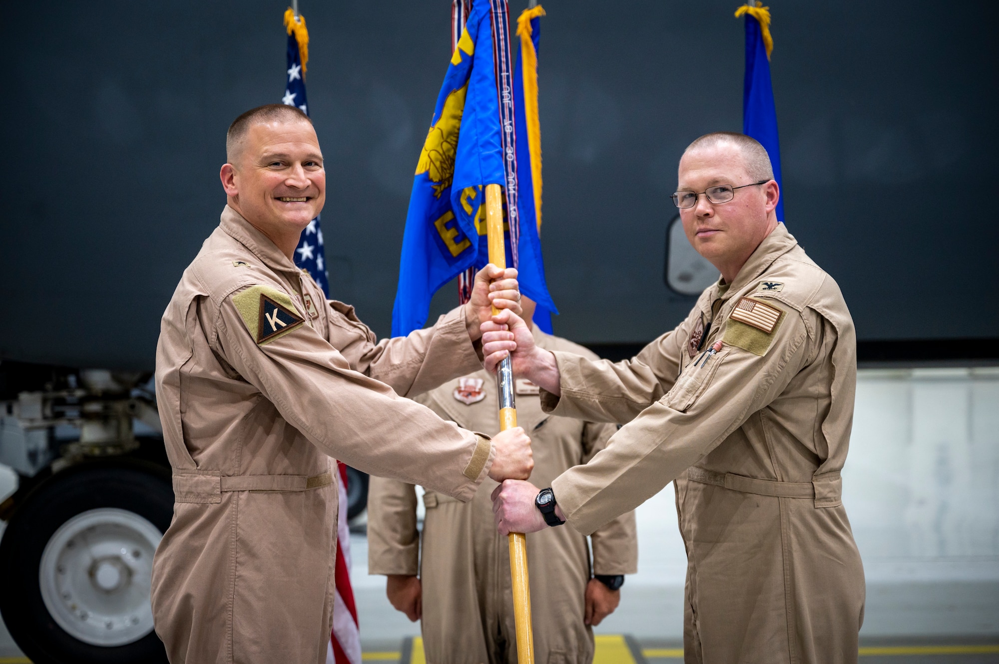 Military members pose for a photo while passing a flag to one another.