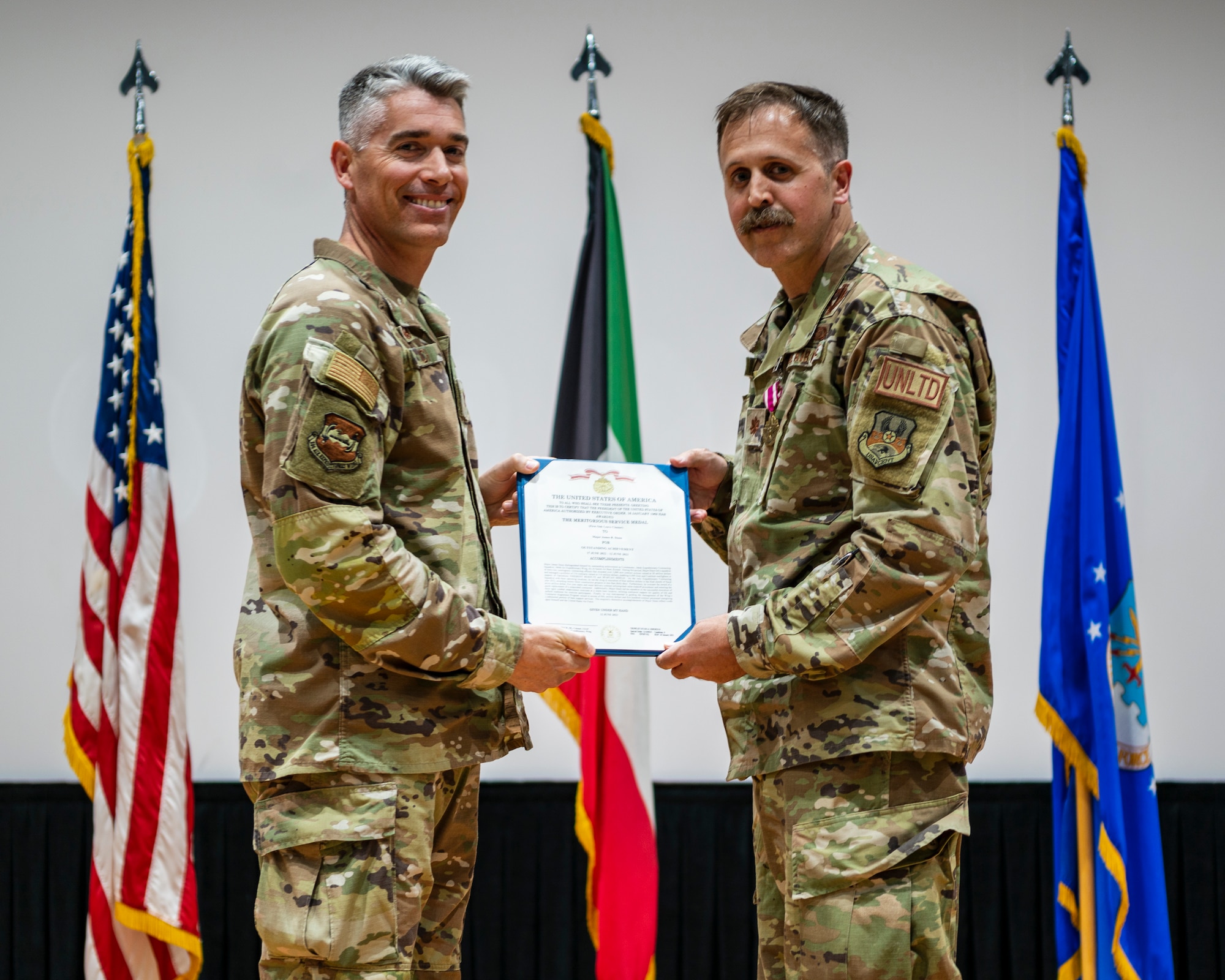 Col. George Buch, Jr., 386th Air Expeditionary Wing commander, presents a Meritorious Service Medal to Maj. James Dunn, outgoing 386th Expeditionary Contracting Squadron commander