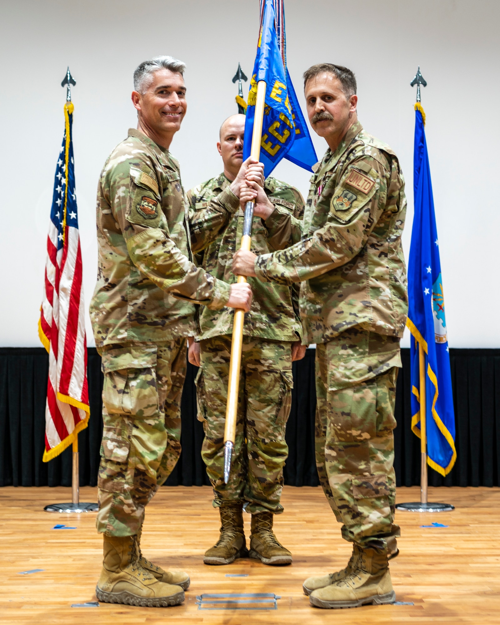 Maj. James Dunn, outgoing 386th Expeditionary Contracting Squadron commander, passes the guidon to Col. George Buch, 386th Air Expeditionary Wing commander, during a change of command ceremony