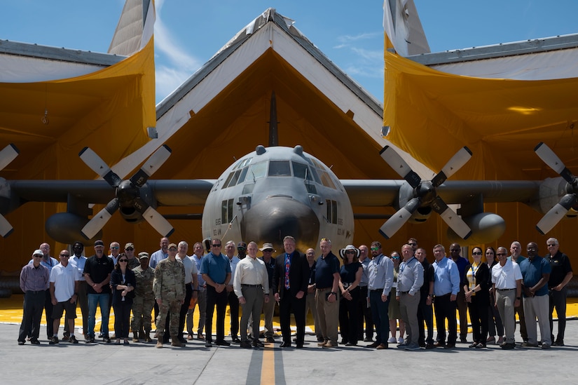 A group stands in front of the JBADS and a C-130 Hercules for a posed photo