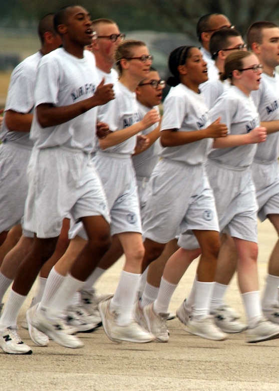 Airmen in white exercise clothes run in formation.
