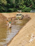 Army personnel in high water pulling out a vehicle