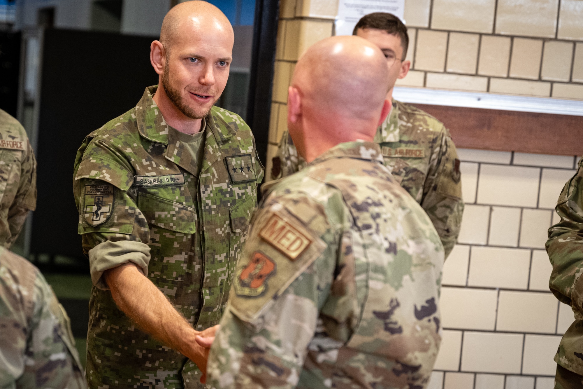 Slovak Armed Forces Capt. Jakub Sasarak, an operations officer for military medical command, shakes hands with an Indiana Air National Guardsman during Innovative Readiness Training mission IRT Hoosier Care at the Terre Haute Boys and Girls Club in Terre Haute, Ind., June 7, 2023. The Indiana National Guard and the Slovak Armed Forces are strategic partners.