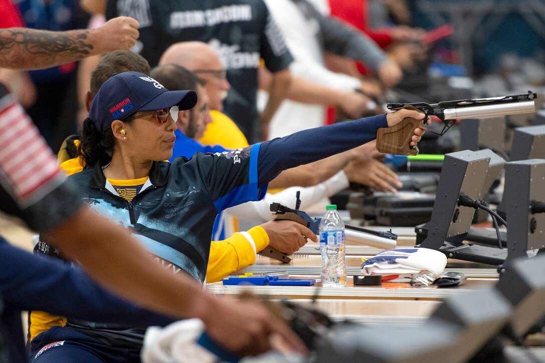 A sailor aims an air pistol among other competitors.