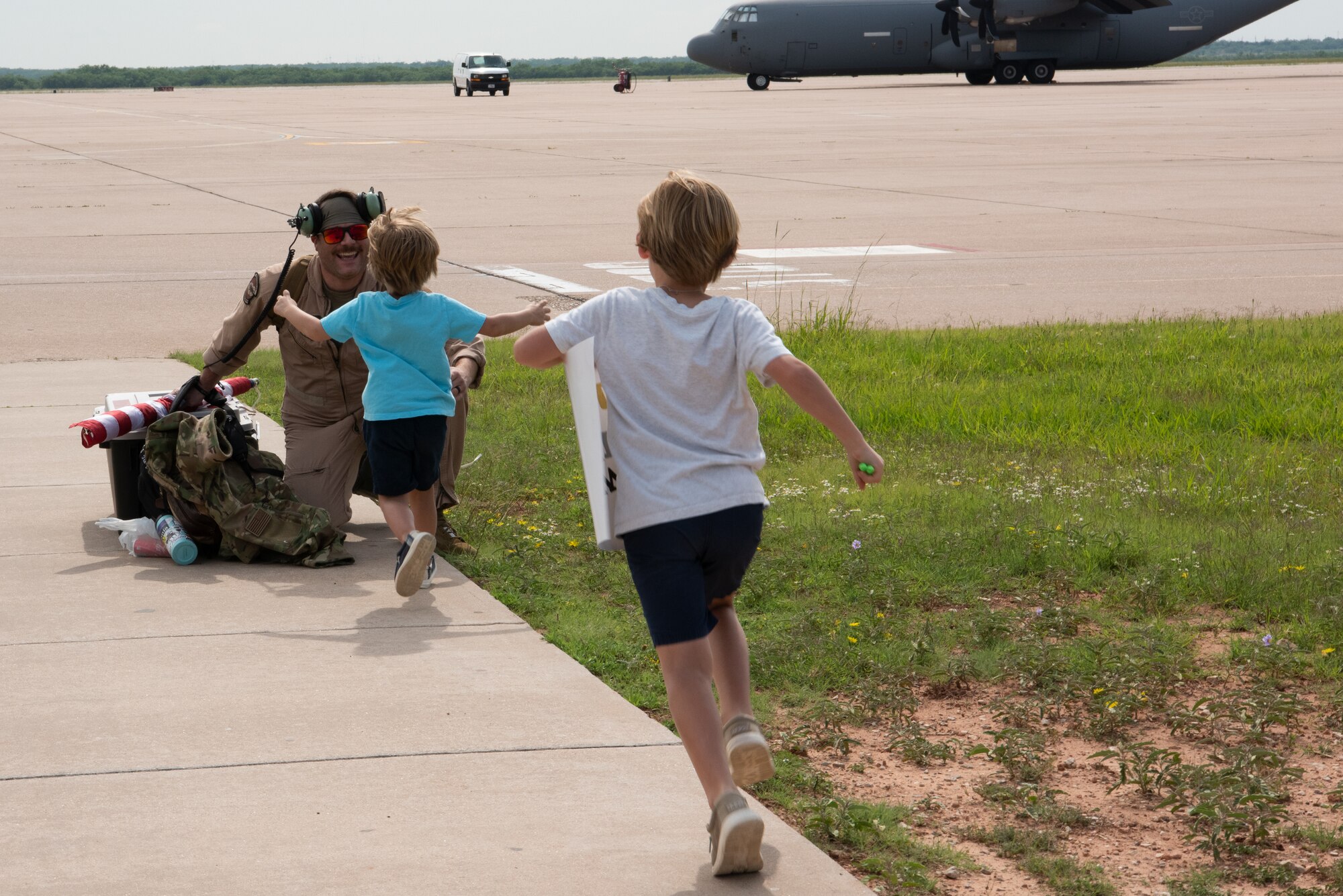 Military children run to their father, a U.S. Air Force Airman from the 317th Airlift Wing, returning from a six-month deployment at Dyess Air Force Base,Texas, June 7, 2023. The 317th AW leadership and family members gathered to welcome home the Airmen after their return from supporting U.S. Central Command taskings. (U.S. Air Force photo by Airman 1st Class Alondra Cristobal Hernandez)