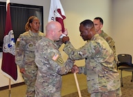 Capt. Matthew Lile, center left, accepts the unit colors from Col. Gary Cooper, commander of U.S. Army Medical Logistics Command, during a Headquarters and Headquarters Detachment change of command ceremony June 9 at Fort Detrick, Maryland. Also pictured are detachment sergeant, Sgt. 1st Class Courtney Price-Davis, and outgoing commander, Maj. Matthew Smith. (U.S. Army photo by C.J. Lovelace)