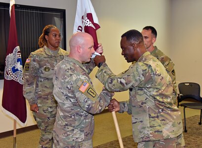 Capt. Matthew Lile, center left, accepts the unit colors from Col. Gary Cooper, commander of U.S. Army Medical Logistics Command, during a Headquarters and Headquarters Detachment change of command ceremony June 9 at Fort Detrick, Maryland. Also pictured are detachment sergeant, Sgt. 1st Class Courtney Price-Davis, and outgoing commander, Maj. Matthew Smith. (U.S. Army photo by C.J. Lovelace)