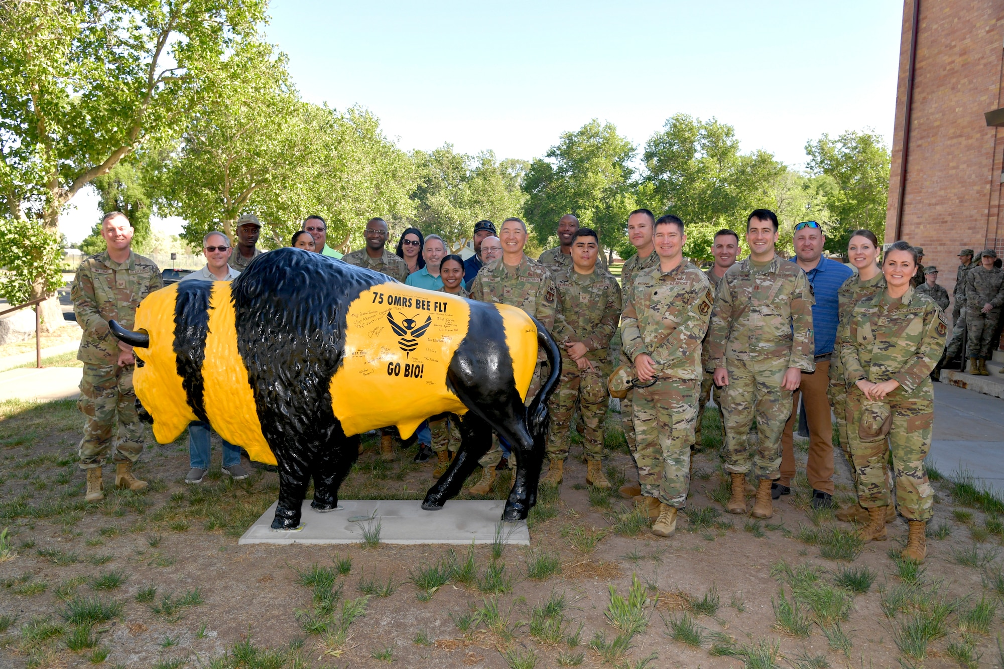 People stand around a steel bison painted in colors like a bee.