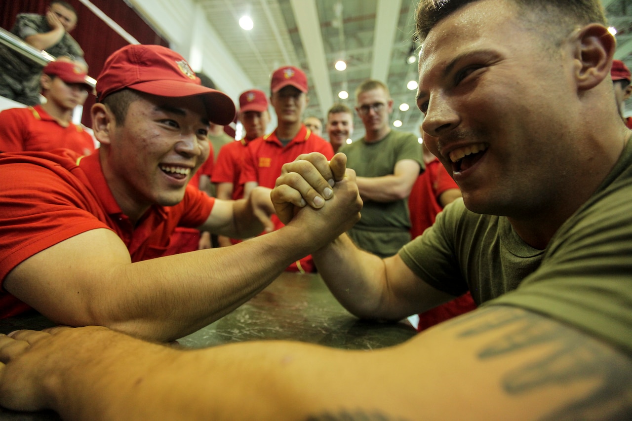 Two men smile as they lock hands for an arm-wrestling match.