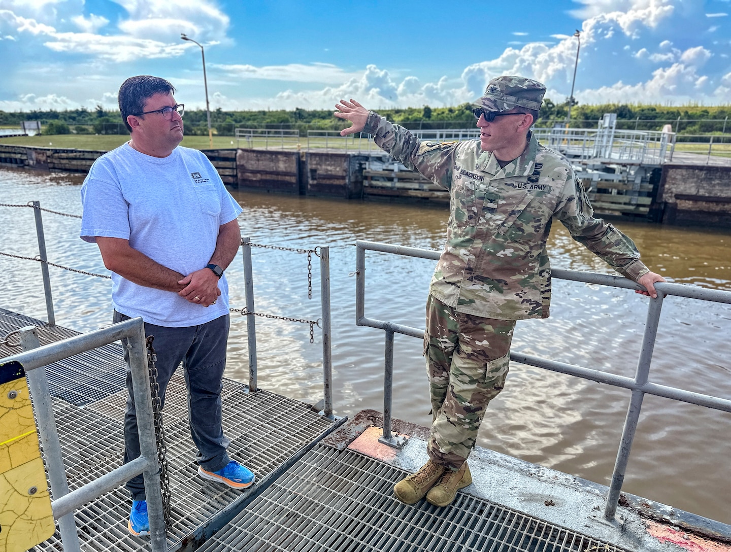 two people are standing outside, next to water, talking