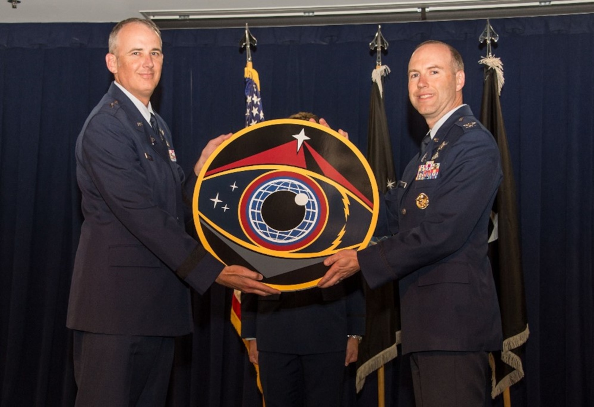 Brig. Gen. Jason Cothern, Space Systems Command, deputy commander, passes the Space Sensing Program Executive Office emblem to Col. Robert Davis, Space Sensing, incoming program executive officer (PEO), during a change of leadership ceremony at SSC headquarters, Los Angeles Air Force Base, California, June 8, 2023. Davis succeeds Col. Brian Denaro, who served as Space Sensing’s PEO once SSC was established as a U.S. Space Force Field Command in August 2021. (U.S. Space Force photo by Van De Ha)