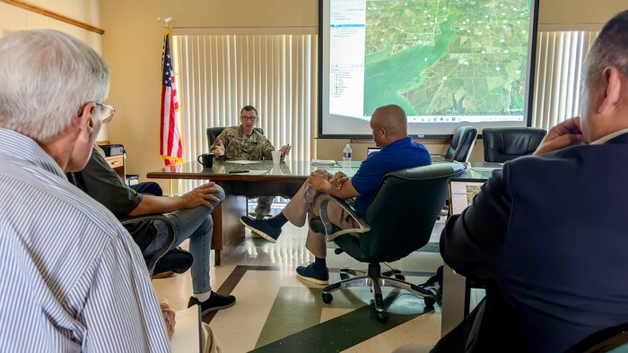 people are seated at a table and around a table while talking