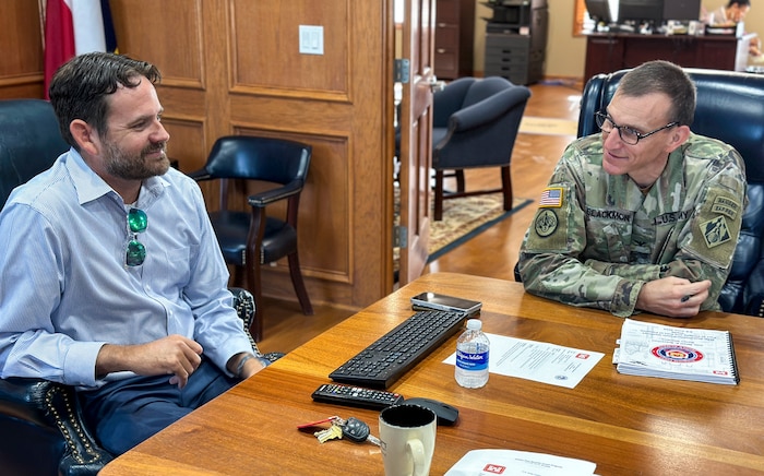 people, one in army uniform, sit at table talking