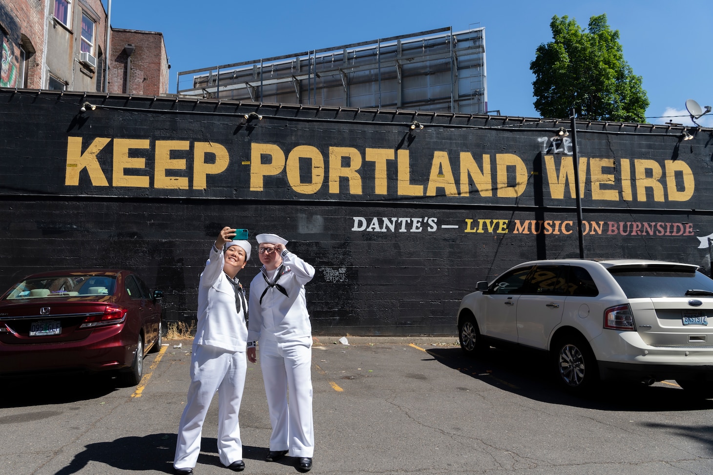 Hospital Corpsman 1st Class Stephanie Fanchiang and Sonar Technician 2nd Class Greylan Smith, both assigned to USS Kansas City (LCS 22), take a selfie in front of a sign during Portland Fleet Week in Portland, Oregon, June 11, 2023. Portland Fleet Week is a time-honored celebration of the sea services and provides an opportunity for the citizens of Oregon to meet Sailors, Marines and Coast Guardsmen, as well as witness firsthand the latest capabilities of today's maritime services. (U.S. Navy photo by Mass Communication Specialist Seaman Sophia H. Bumps)