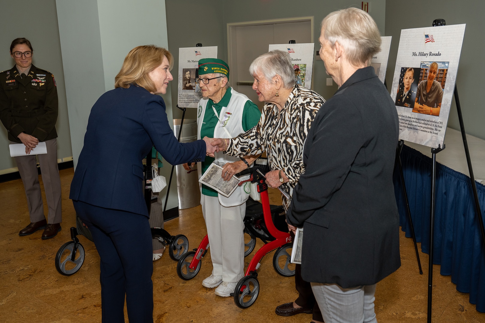 Deputy Defense Secretary Kathleen H. Hicks shakes hands with a veteran as others stand by.