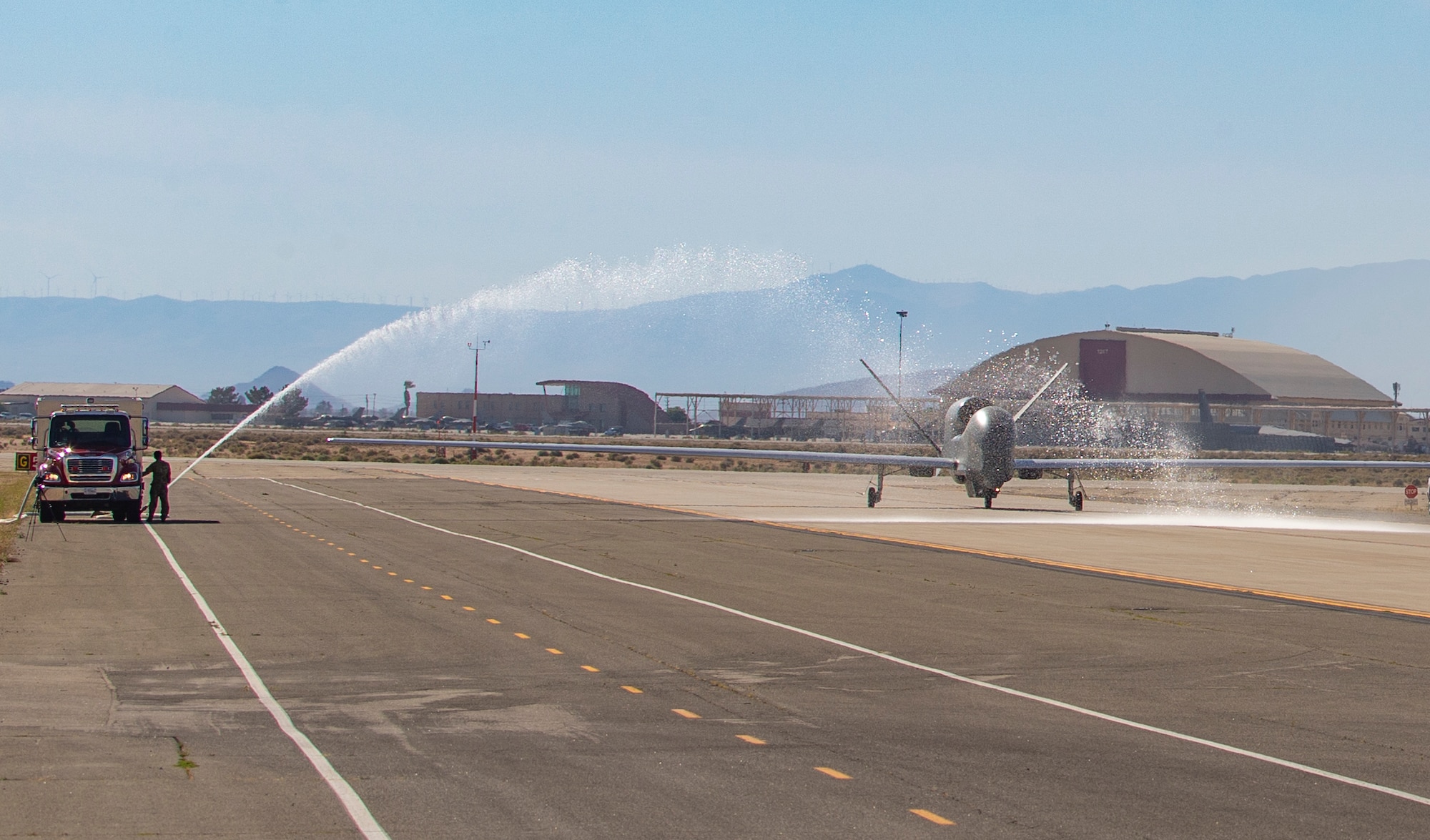 Fire trucks from the 812th Civil Engineer Squadron provide a water salute to an RQ-4 Global Hawk, assigned to and operated  by the 452nd Flight Test Squadron, at Edwards Air Force Base, California, May 23.The water salute was in honor of the 452nd FLTS's final test flight of the RQ-4. (Air Force photo by Todd Schannuth)